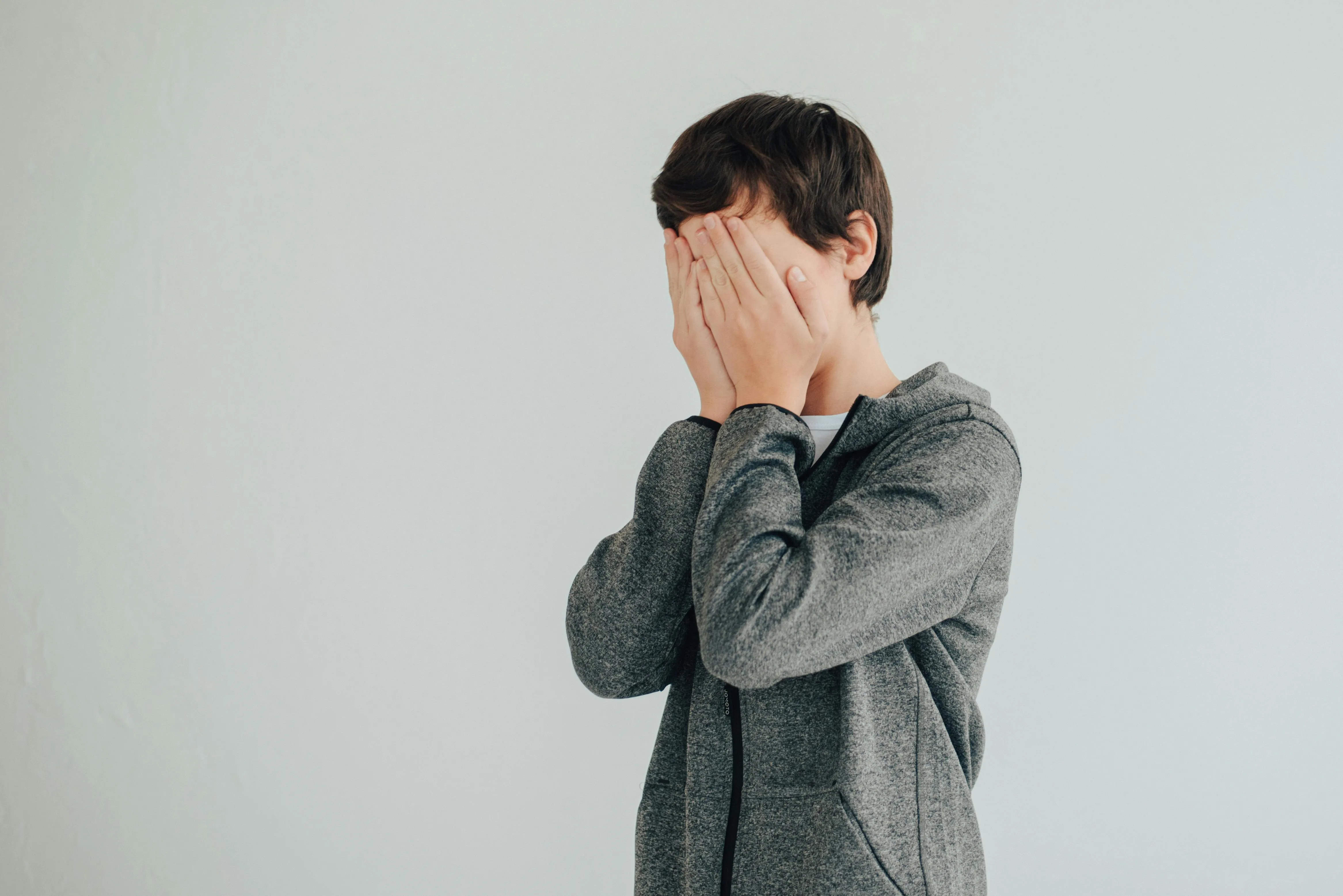 A teenager who is covering his face to hide