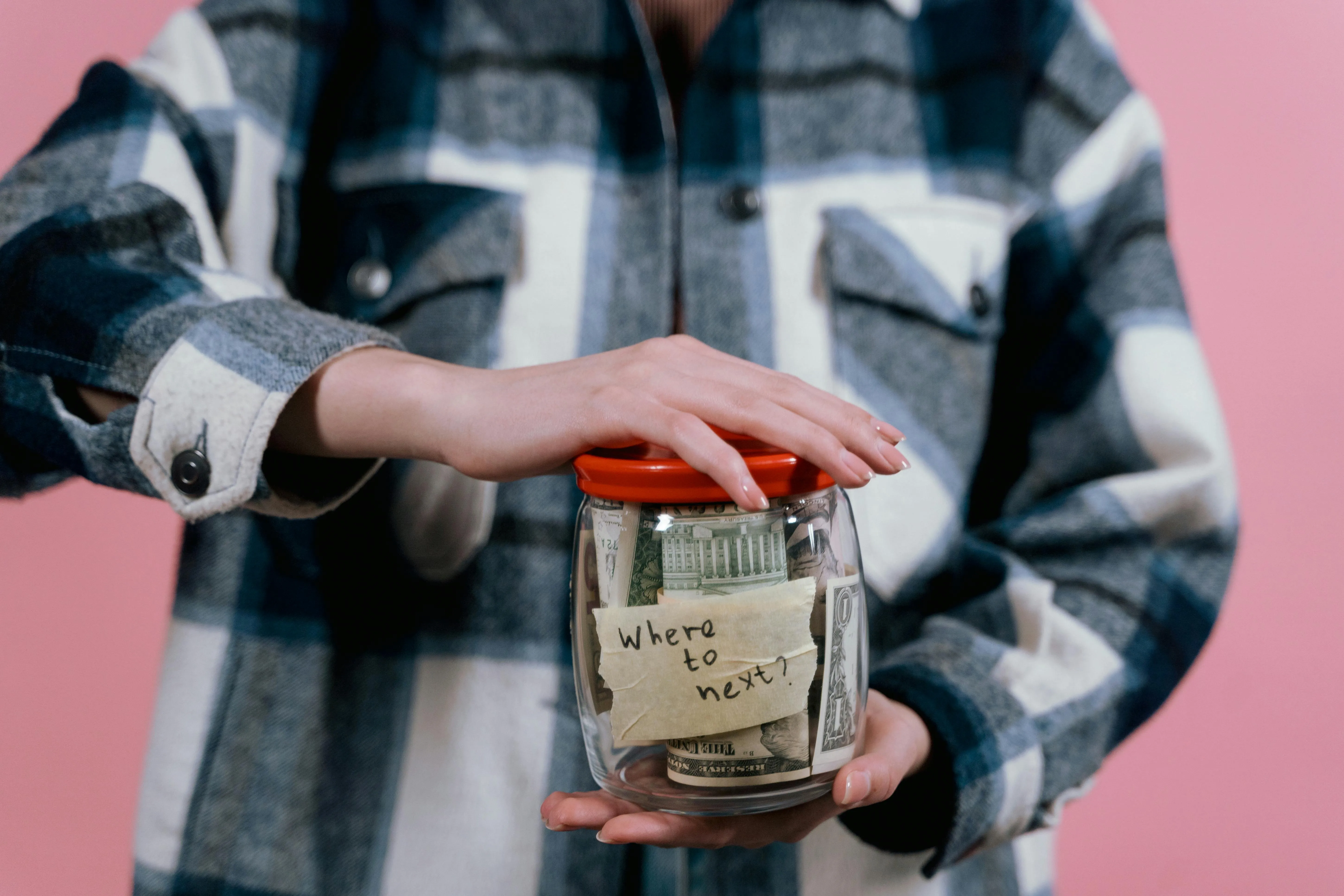 Two hands holding a jar with money in it, the jar is labled “College Savings”